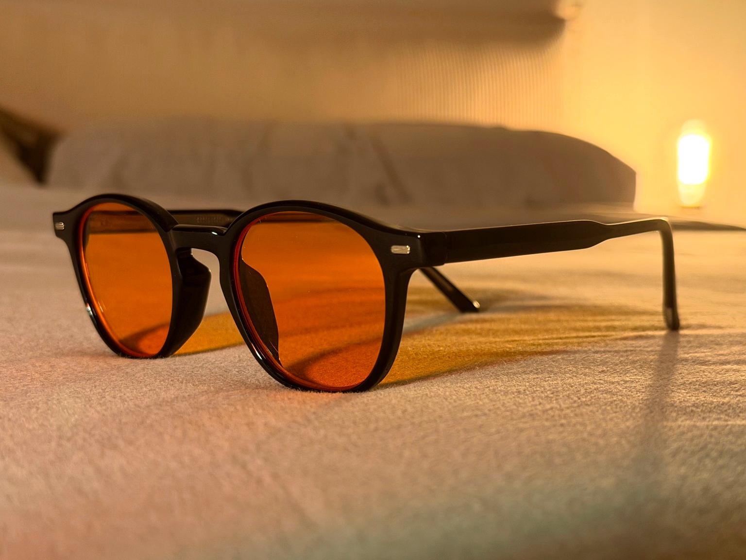 nightshift orange-tinted night glasses on a bed in warm lighting