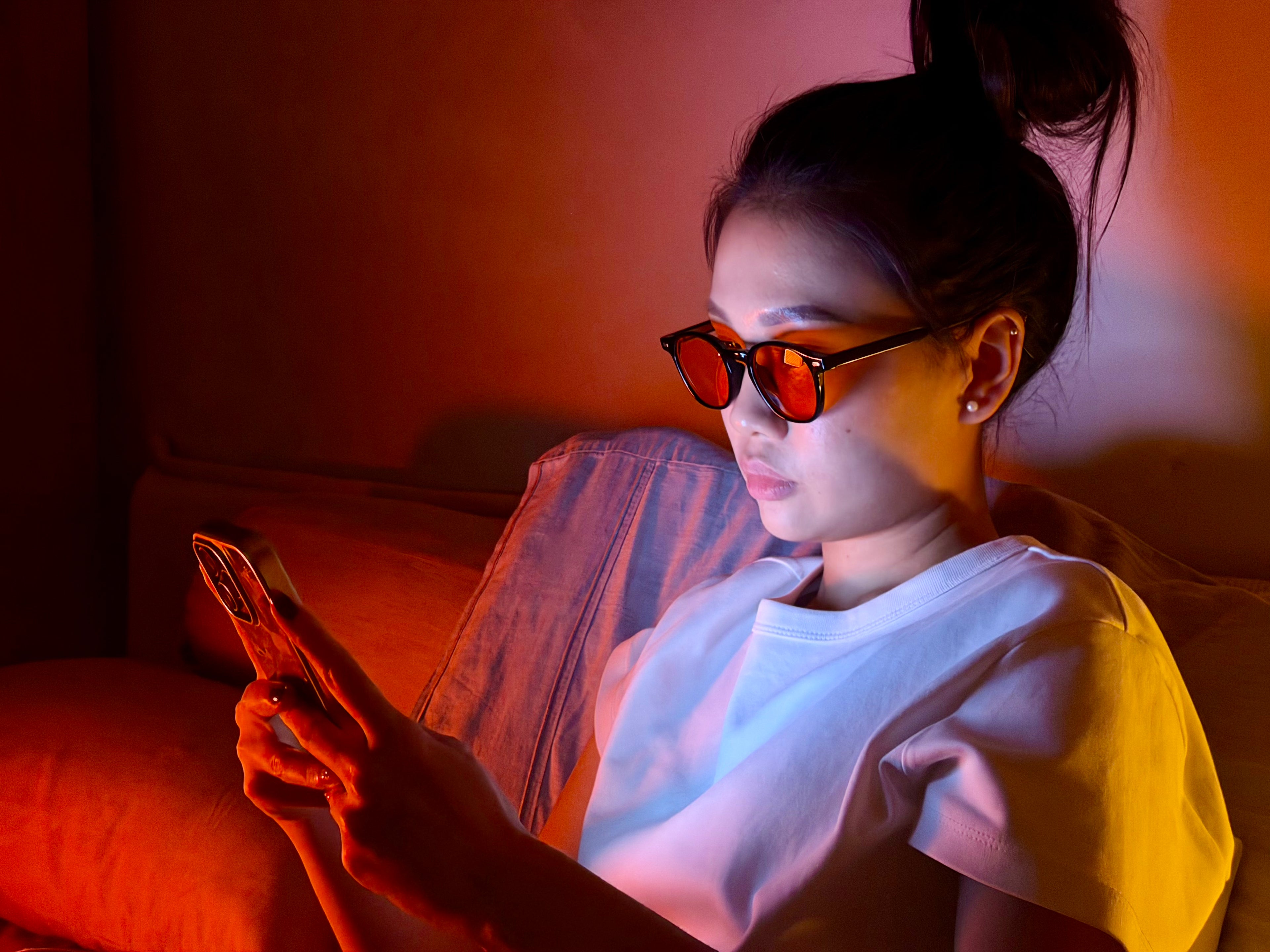 Person wearing sunglasses using a phone in a dimly lit room